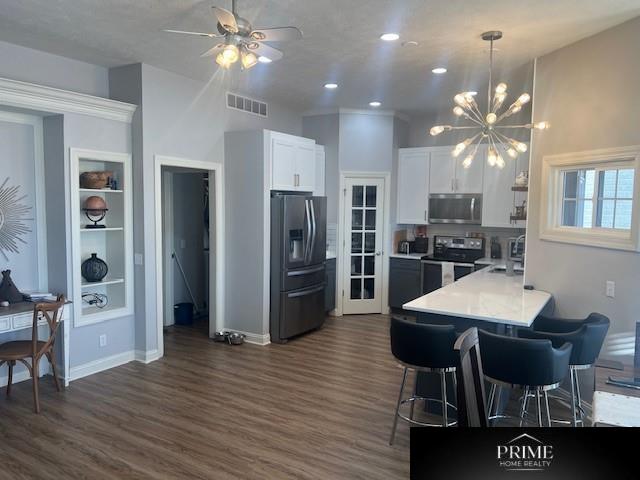 kitchen featuring visible vents, white cabinets, light countertops, appliances with stainless steel finishes, and a kitchen bar