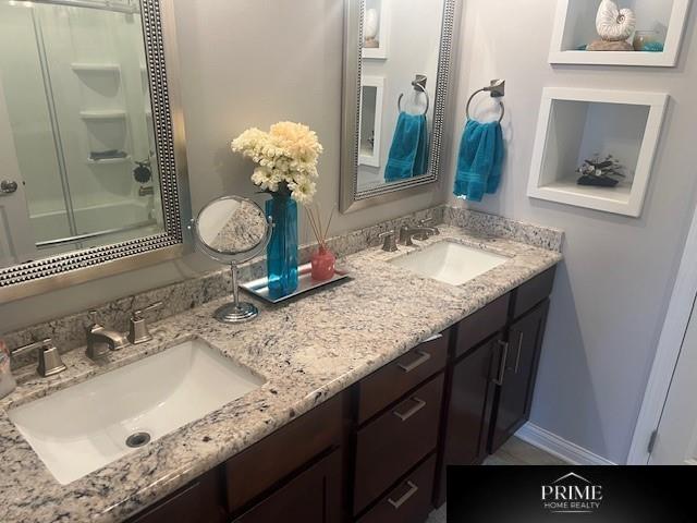 bathroom with double vanity, a sink, and baseboards