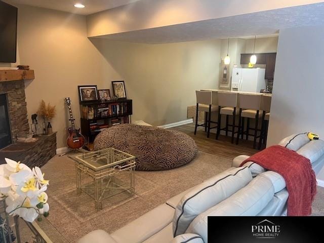 living room with recessed lighting, a stone fireplace, baseboards, and wood finished floors