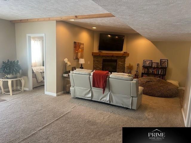 carpeted living area with a textured ceiling, a fireplace, and baseboards