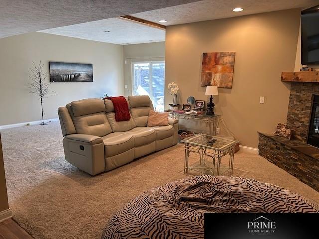 living room featuring a textured ceiling, recessed lighting, light colored carpet, a fireplace, and baseboards