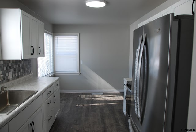 kitchen with light countertops, white cabinets, a sink, and freestanding refrigerator