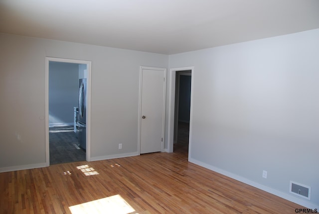 unfurnished room featuring light wood-style flooring, visible vents, and baseboards