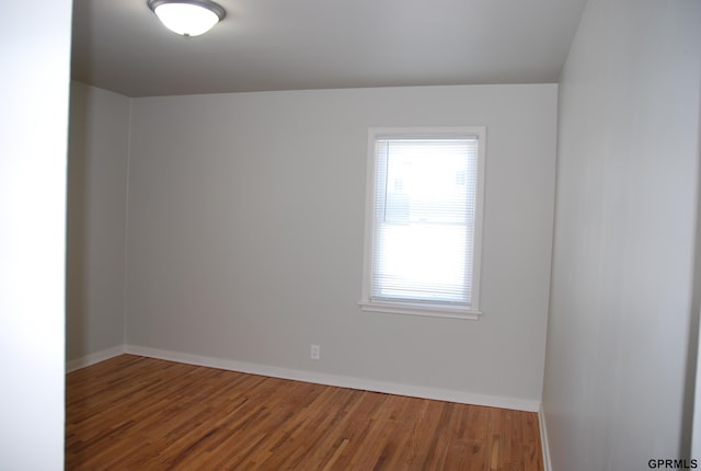 spare room featuring baseboards and wood finished floors