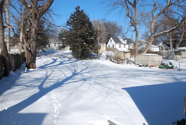 yard layered in snow with a residential view and fence