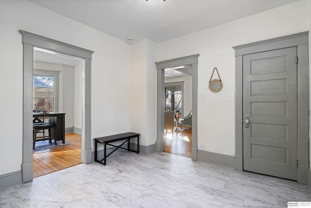 entrance foyer featuring marble finish floor and baseboards