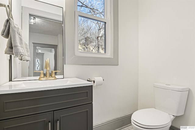 bathroom with baseboards, vanity, and toilet