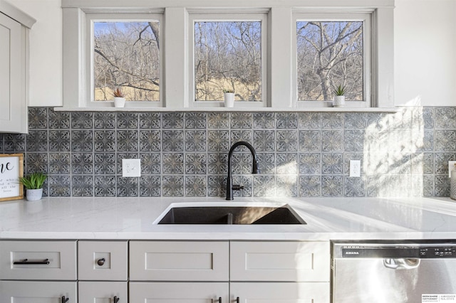 kitchen featuring a sink, light stone countertops, white cabinets, and dishwasher