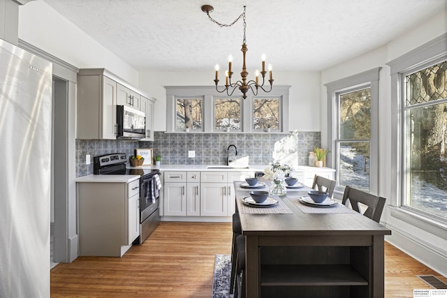 kitchen featuring light wood finished floors, pendant lighting, stainless steel appliances, and light countertops