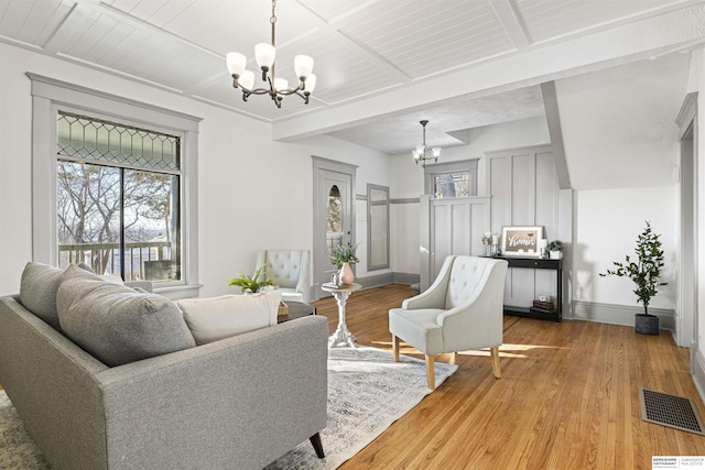 living area featuring a chandelier, visible vents, plenty of natural light, and wood finished floors