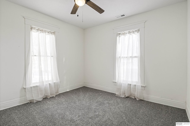 empty room with visible vents, dark carpet, and baseboards