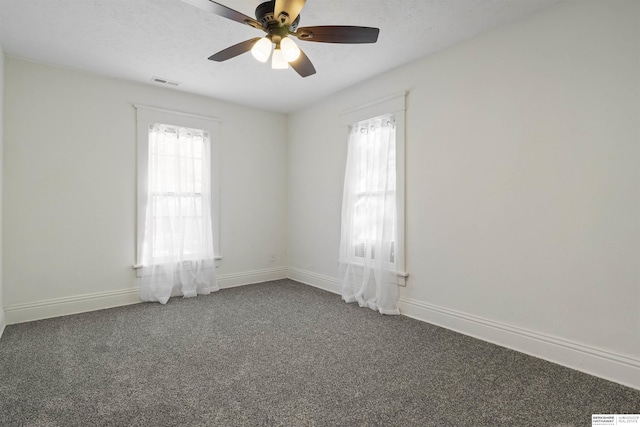 unfurnished room with visible vents, dark carpet, a textured ceiling, and baseboards