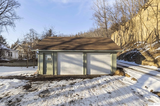 snow covered garage featuring a detached garage