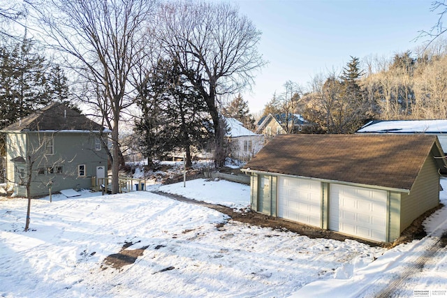 snowy yard with an outbuilding and a detached garage