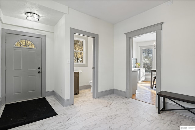 entryway with marble finish floor and baseboards