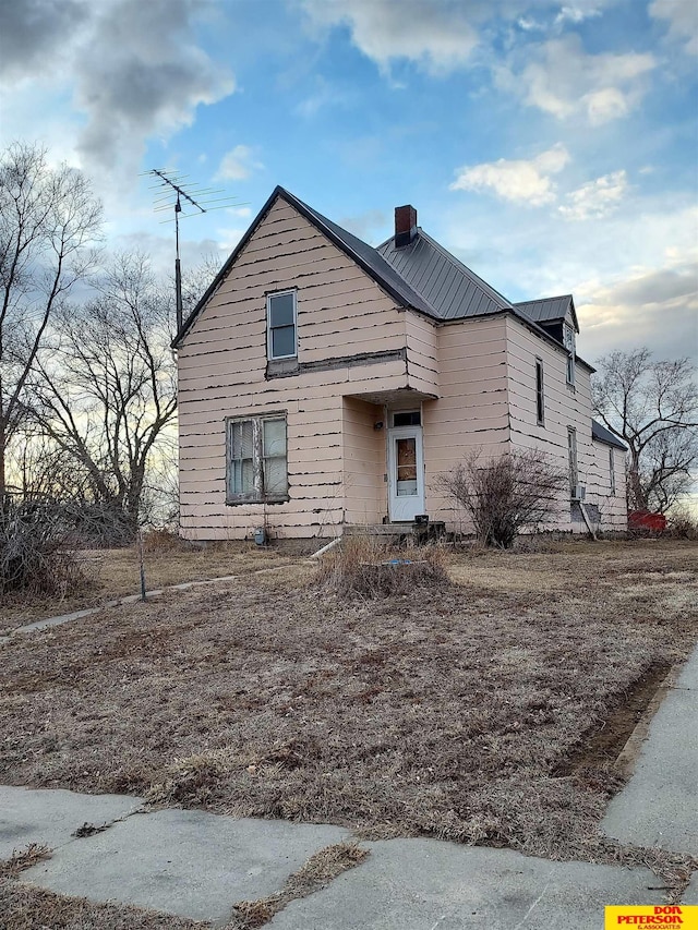 view of front of property featuring metal roof and a chimney