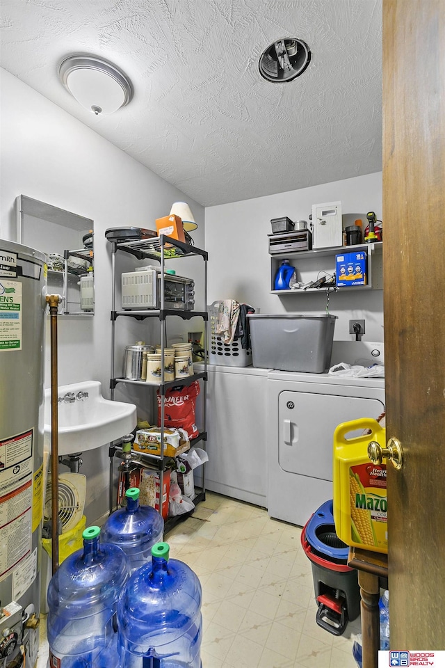 washroom featuring laundry area, washing machine and clothes dryer, a textured ceiling, light floors, and water heater