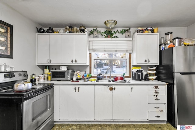 kitchen featuring a toaster, stainless steel appliances, a sink, white cabinets, and light countertops