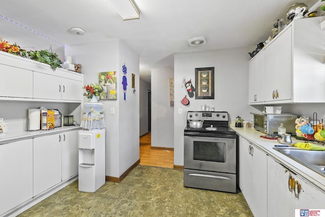 kitchen with light countertops, white cabinets, and stainless steel electric range