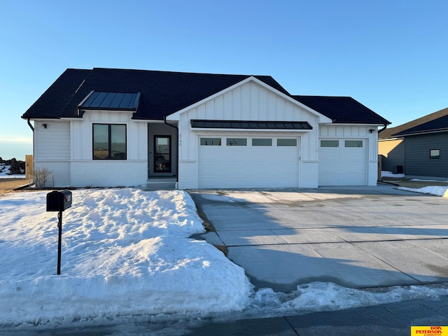 modern farmhouse style home with an attached garage, brick siding, driveway, board and batten siding, and a standing seam roof