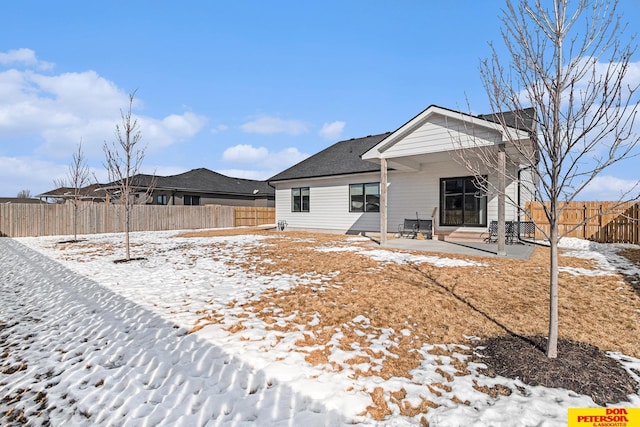 snow covered rear of property featuring a fenced backyard