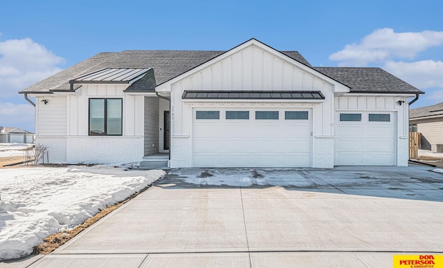 modern farmhouse style home with an attached garage, brick siding, a shingled roof, driveway, and board and batten siding