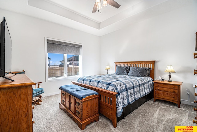 bedroom with baseboards, a tray ceiling, a ceiling fan, and light colored carpet