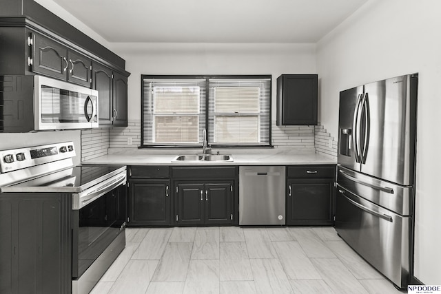 kitchen featuring stainless steel appliances, light countertops, decorative backsplash, a sink, and dark cabinets