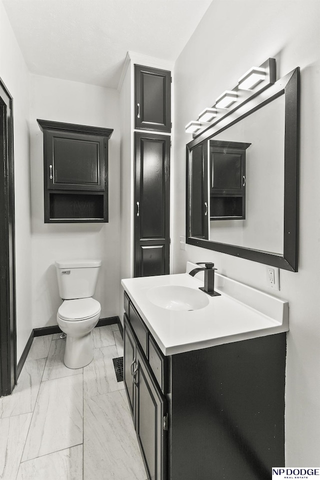 half bathroom featuring marble finish floor, toilet, vanity, and baseboards