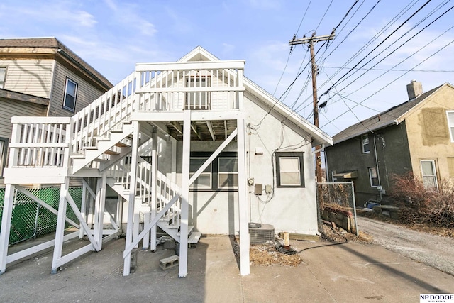 rear view of house featuring stucco siding and stairs