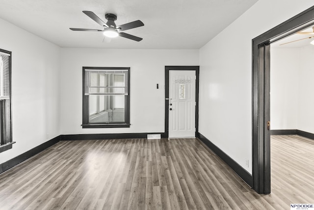 interior space featuring a ceiling fan, baseboards, and wood finished floors