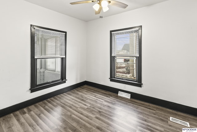 spare room with a ceiling fan, wood finished floors, visible vents, and baseboards