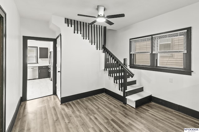 stairway featuring a healthy amount of sunlight, wood finished floors, and baseboards