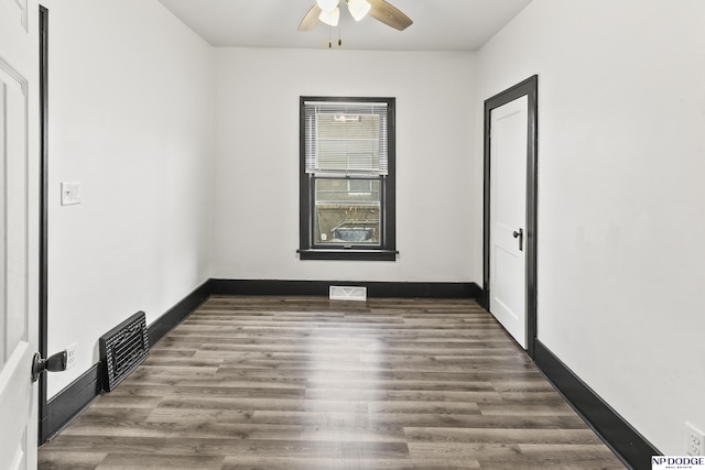 empty room with baseboards, visible vents, and dark wood-style flooring