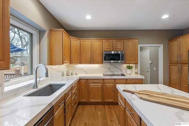 kitchen with recessed lighting, a sink, light wood-style floors, light stone countertops, and stainless steel microwave