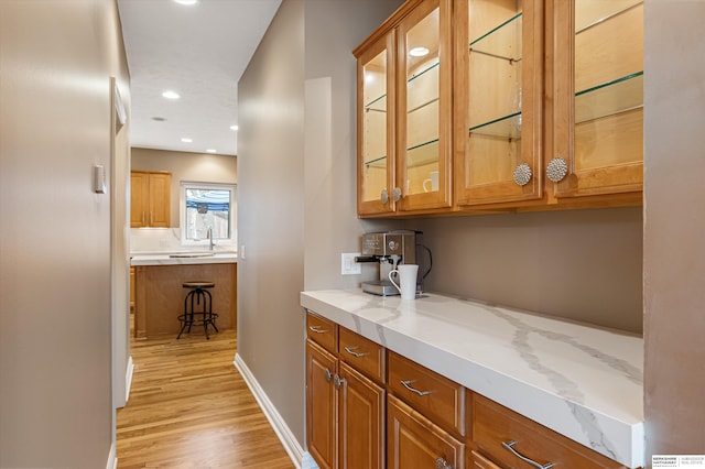 bar with baseboards, recessed lighting, a sink, and light wood-style floors