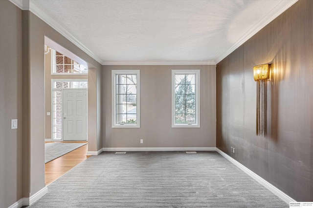 entryway featuring baseboards, a textured ceiling, carpet flooring, and crown molding