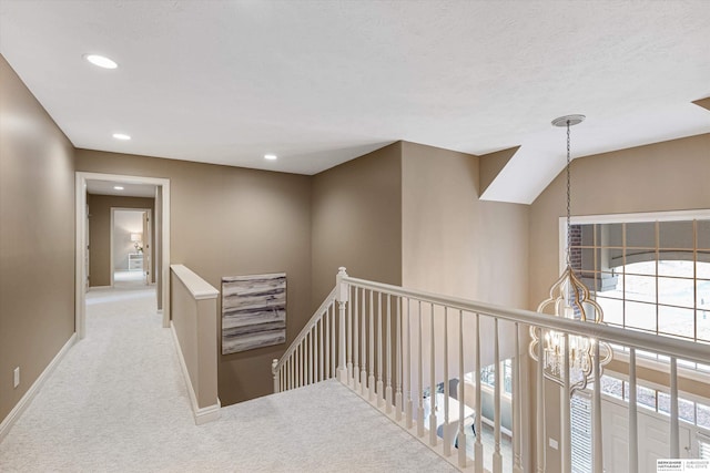 corridor featuring recessed lighting, carpet flooring, an upstairs landing, baseboards, and an inviting chandelier