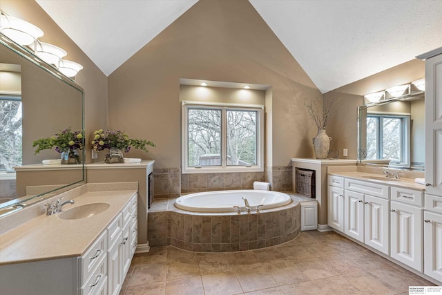 full bath with two vanities, vaulted ceiling, and a sink