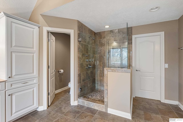 full bath with a stall shower, baseboards, a textured ceiling, and toilet