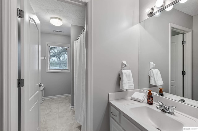 bathroom with baseboards, visible vents, a textured ceiling, and vanity