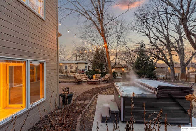 yard at dusk featuring a hot tub, fence, and a fire pit