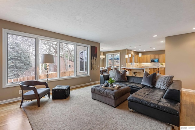 living area with a wealth of natural light, baseboards, and light wood finished floors