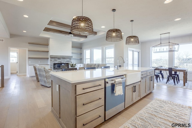 kitchen featuring open floor plan, light countertops, hanging light fixtures, dishwasher, and an island with sink