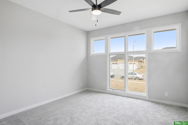 carpeted empty room featuring ceiling fan, visible vents, and baseboards