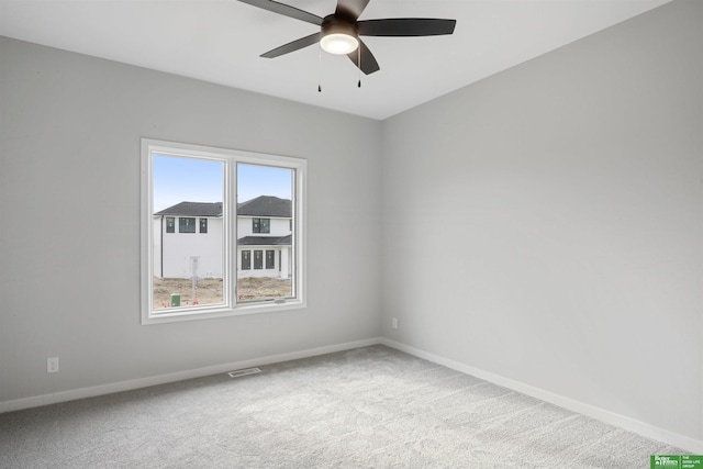 empty room with a ceiling fan, carpet flooring, visible vents, and baseboards