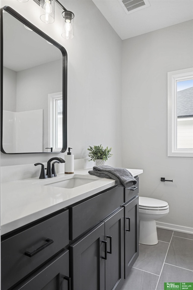 bathroom featuring tile patterned flooring, toilet, vanity, visible vents, and baseboards