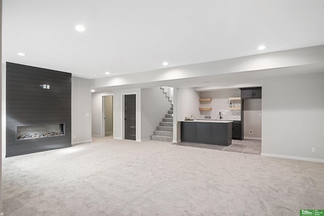 unfurnished living room featuring recessed lighting, a large fireplace, light colored carpet, and stairs