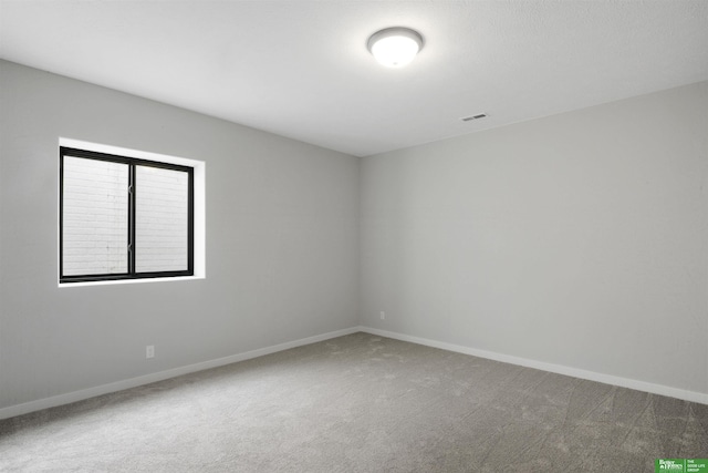 carpeted spare room with visible vents and baseboards