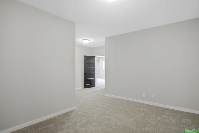 carpeted spare room featuring baseboards